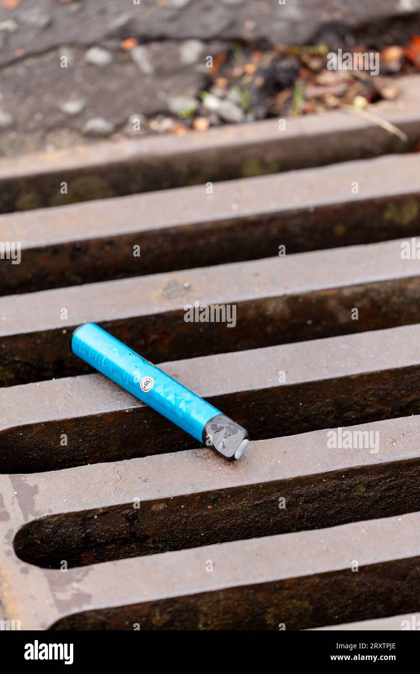 Single use disposable vape lying on a road drain Stock Photo