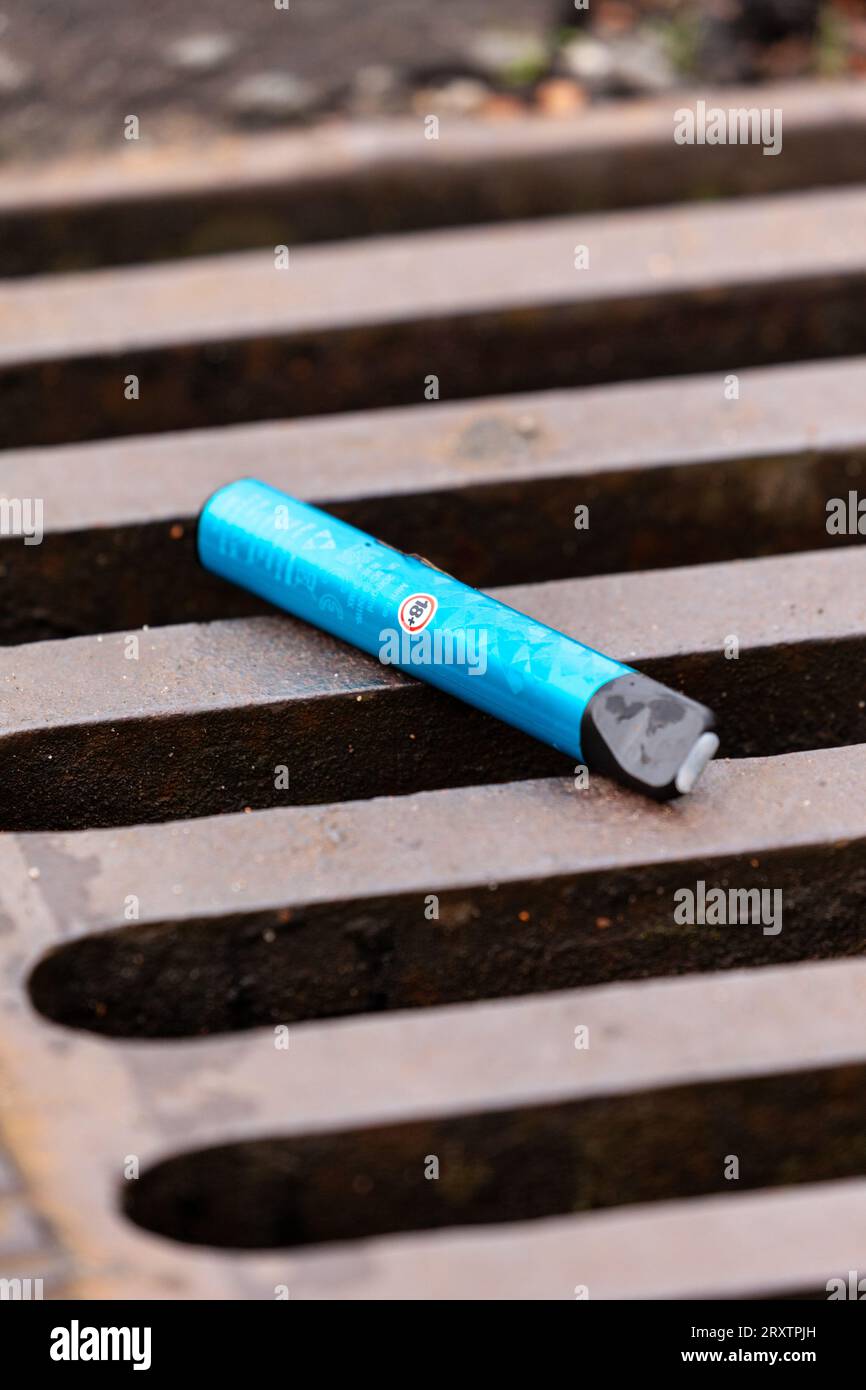 Single use disposable vape lying on a road drain Stock Photo