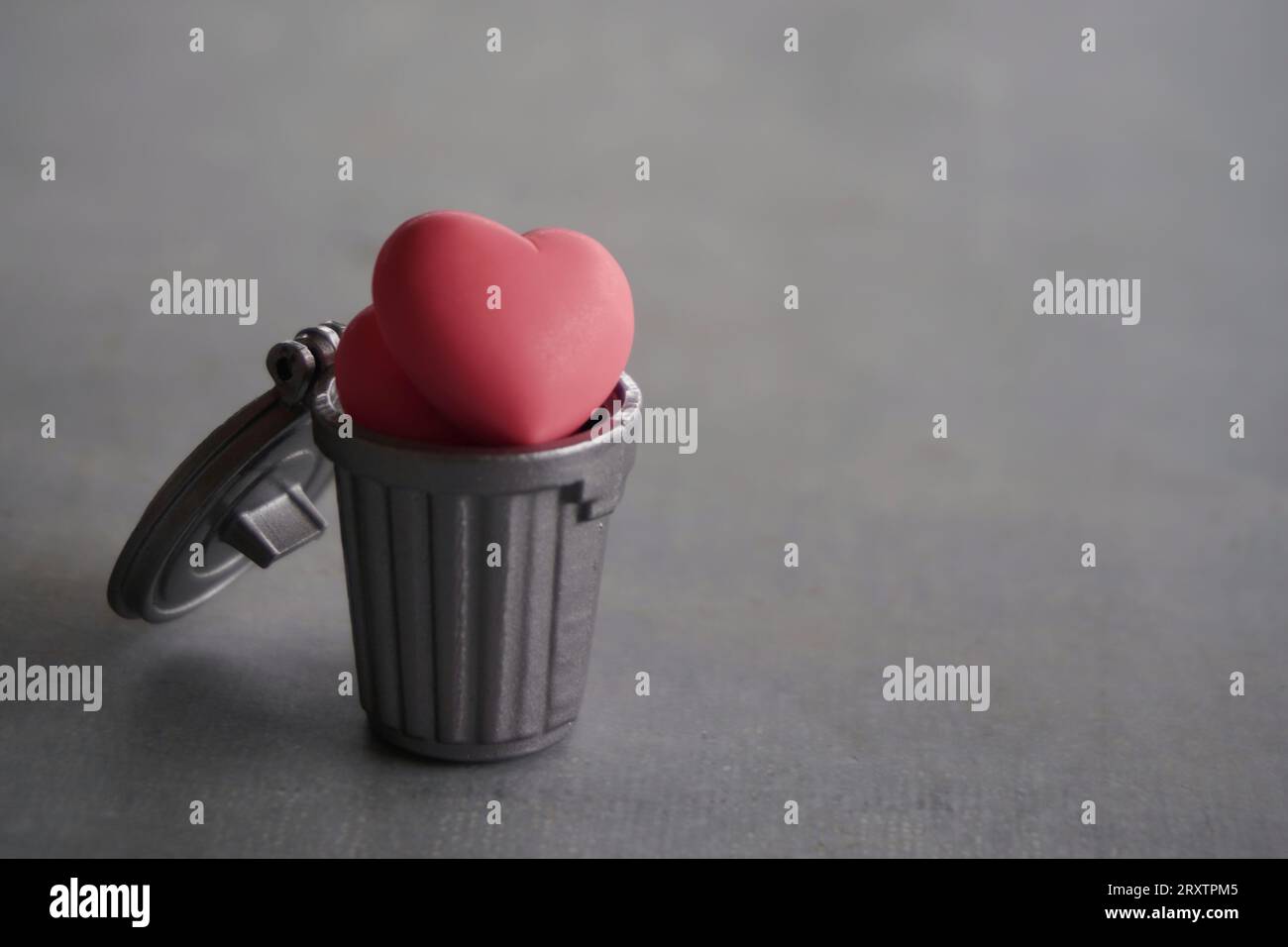 Closeup image of heart inside trash can with copy space. Broken heart, heartless, frustrated and rejection concept. Stock Photo