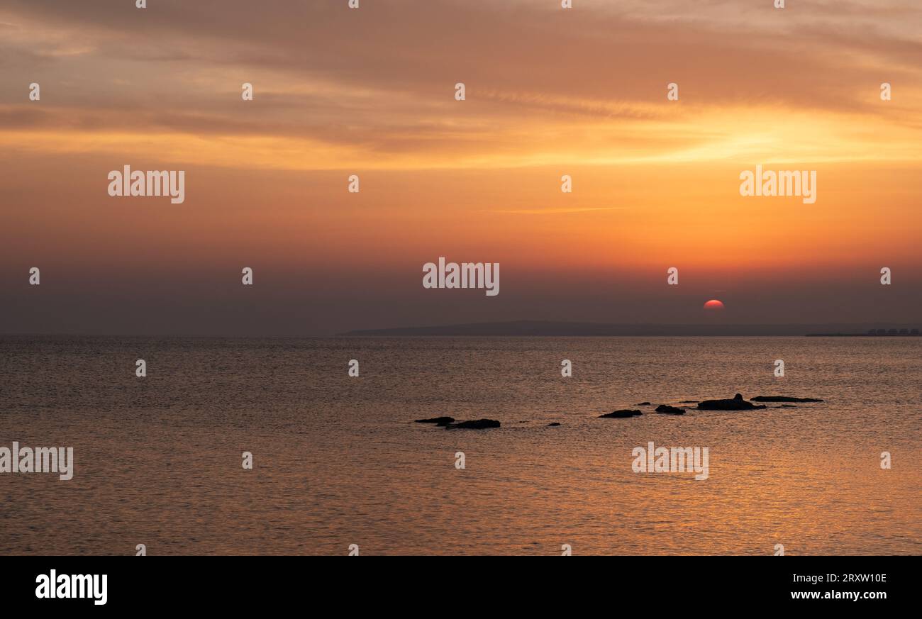 Dramatic beautiful sunset in the coast. Orange colours cloudy sky. End of day. Sun on the horizon Stock Photo