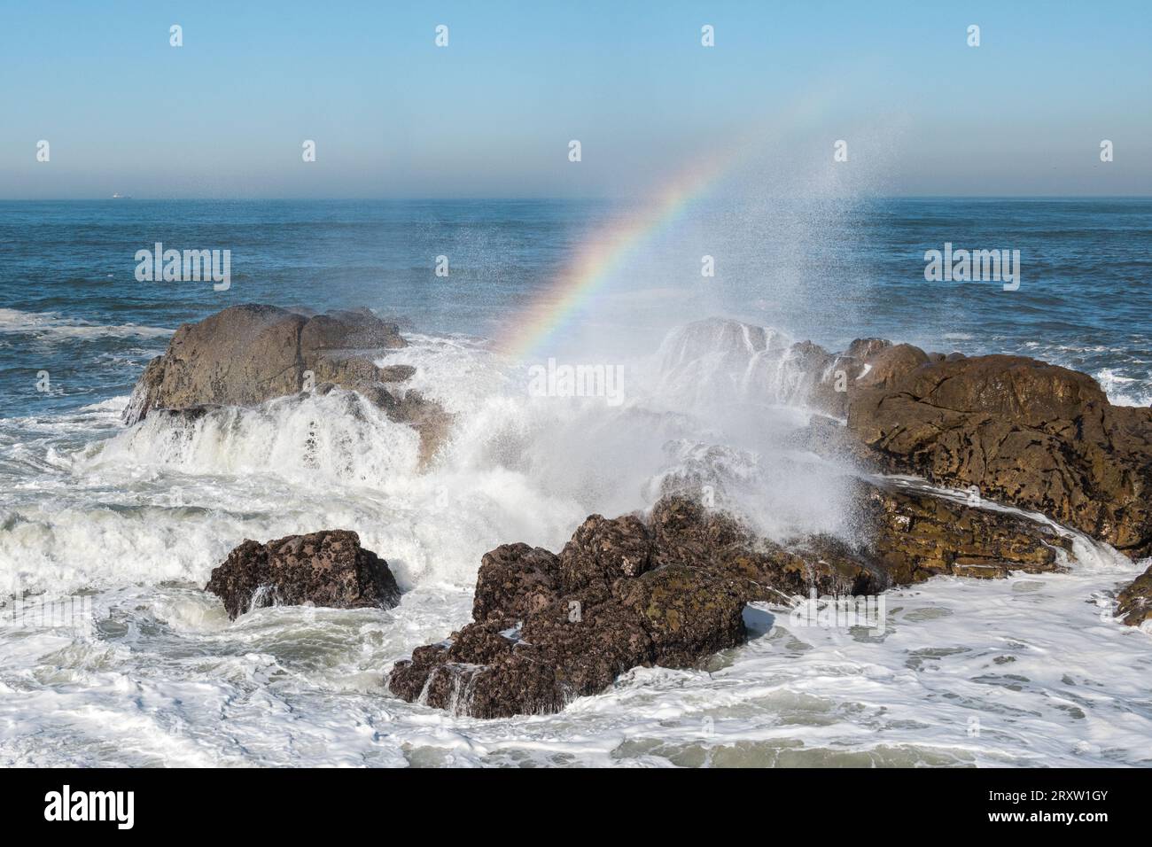 Waves and rainbow in the sea coast Stock Photo