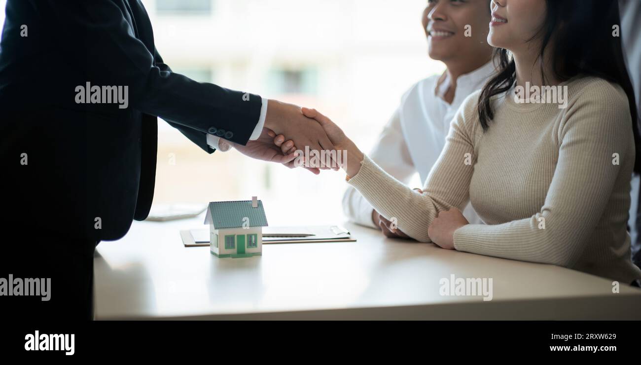 Real estate asian agent shakes hands with husband and wife customer