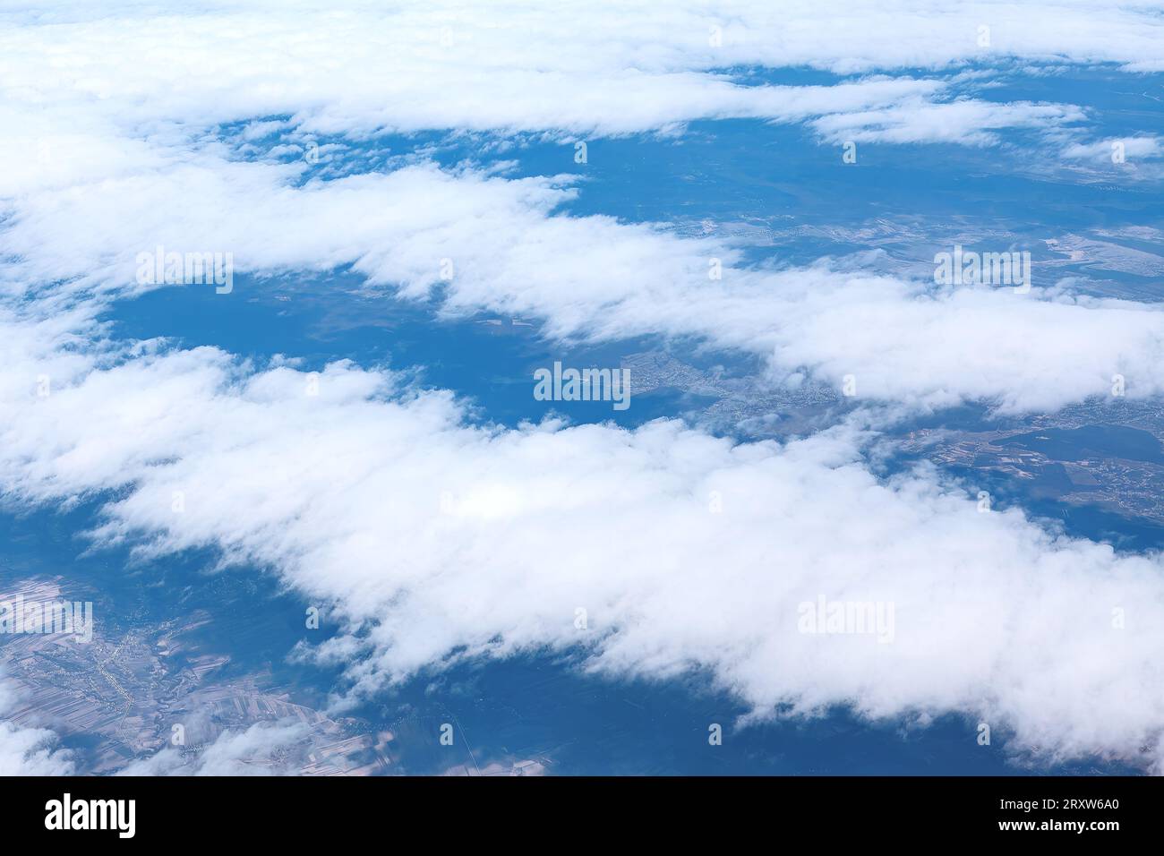 Clouds in the blue sky and earth as seen through window of an aircraft Stock Photo