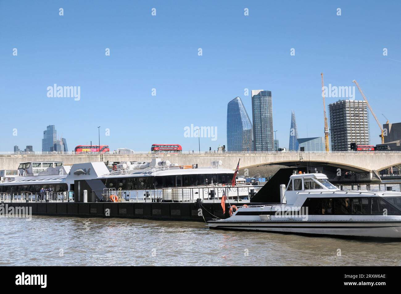 View from Victoria Embankment on a sunny day with boats on River Thames, skyscrapers on London skyline and red buses crossing Waterloo Bridge. UK Stock Photo