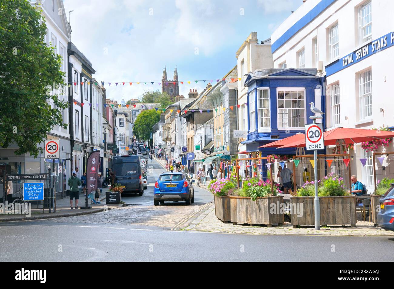 View looking up Fore Street in Totnes town centre with independent shops and cafes and St Mary's Parish Church, South Hams, South Devon, England, UK Stock Photo