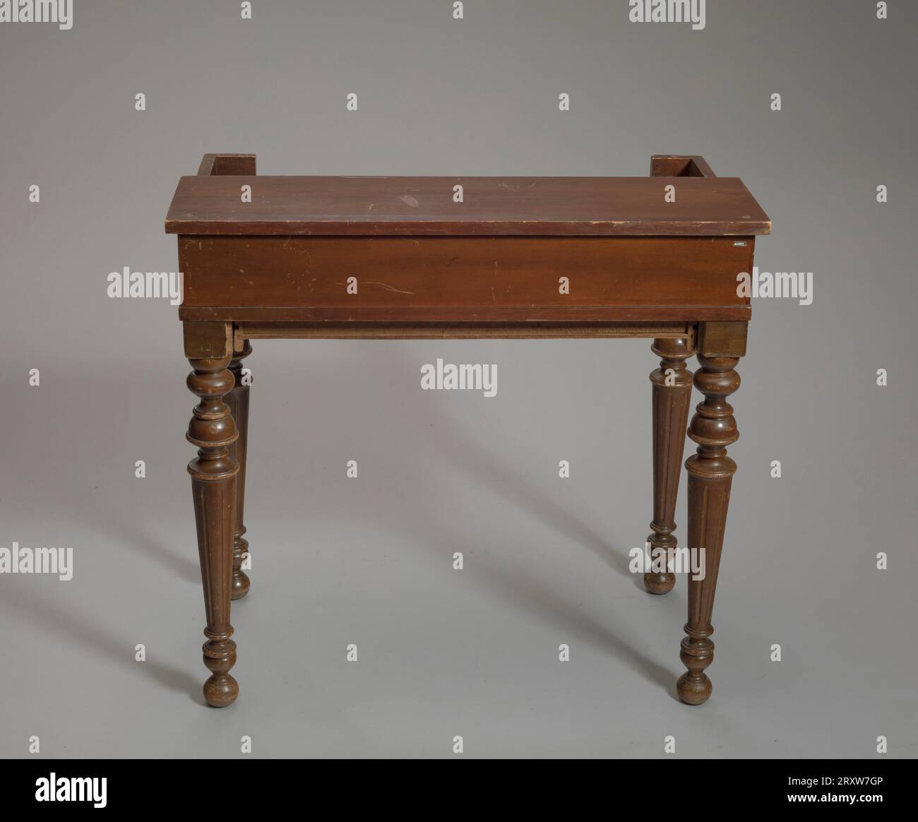 https://c8.alamy.com/comp/2RXW7GP/wooden-writing-desk-with-four-fluted-legs-at-the-front-below-the-mid-section-on-either-side-are-long-rectangles-of-wood-with-angled-triangles-extending-out-from-center-the-desk-has-four-cubby-holes-below-a-shelf-on-the-back-of-the-writing-surface-there-is-a-pair-of-cubbies-on-either-side-of-the-desks-writing-surface-as-well-the-writing-surface-slides-in-and-out-of-mid-section-with-two-hand-holds-for-easy-access-on-either-side-of-the-top-near-the-front-the-front-portion-of-the-writing-top-is-slightly-curved-the-desk-has-a-large-rectangular-drawer-with-scalloped-lower-edges-on-the-front-2RXW7GP.jpg