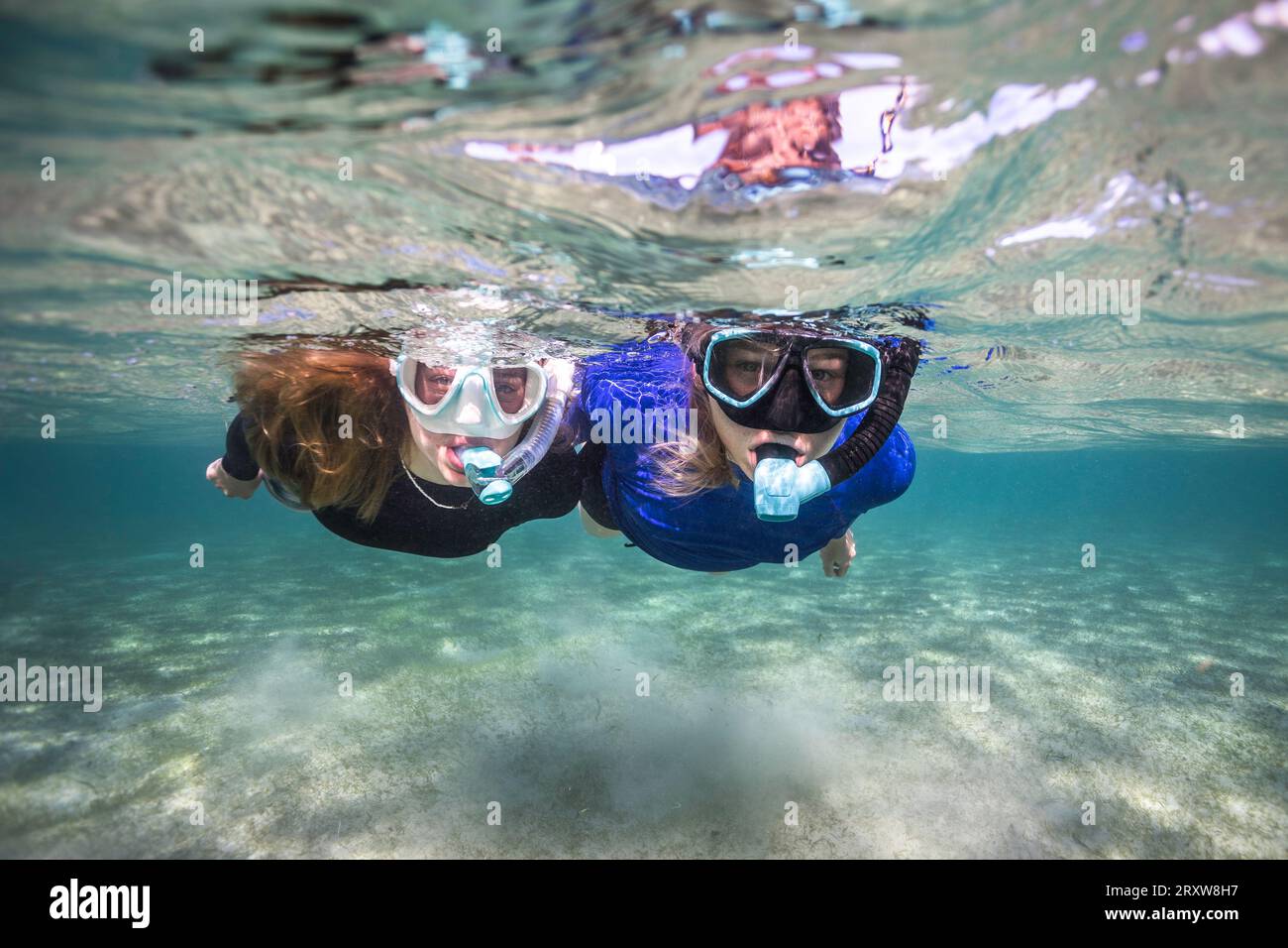 Two snorkelers in clear water looking at the camera floating on the water surface Stock Photo