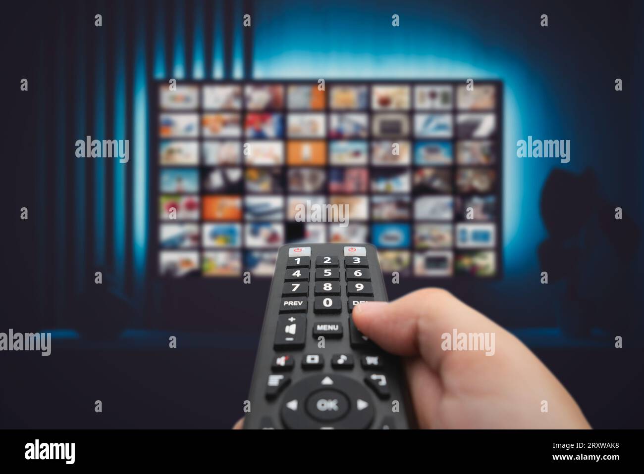 VOD service screen. Man watching TV with remote control in hand. Stock Photo