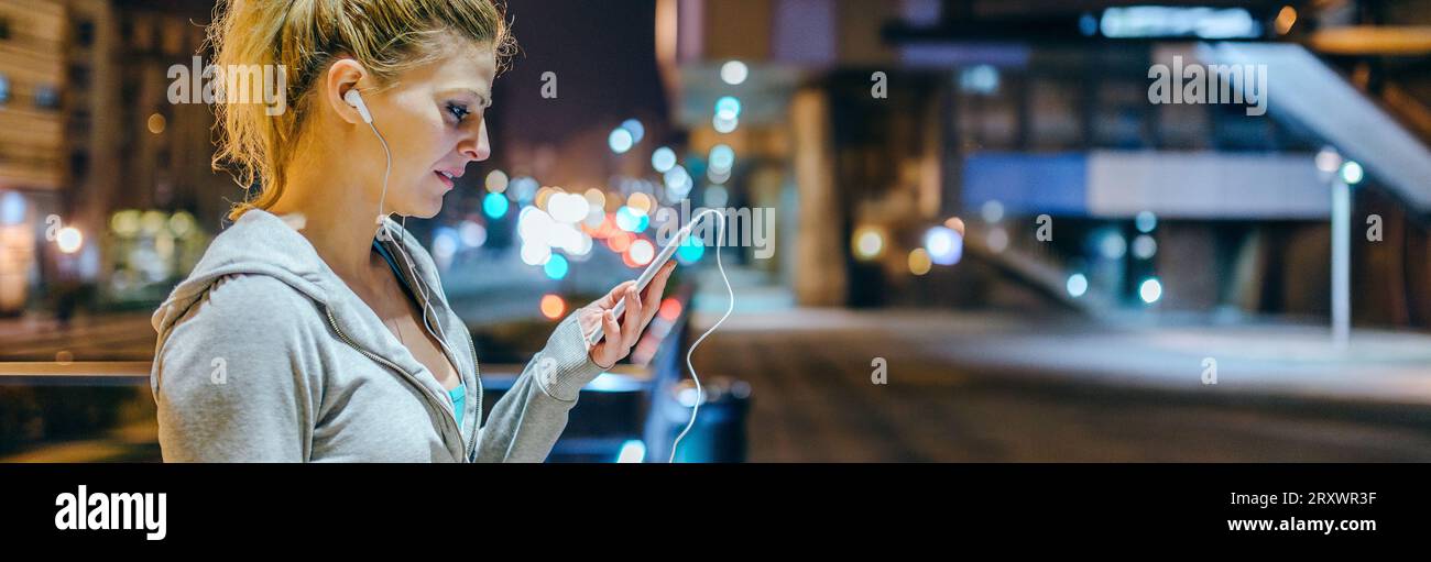 Young blonde sportswoman checking exercise progress on tracker mobile phone application Stock Photo