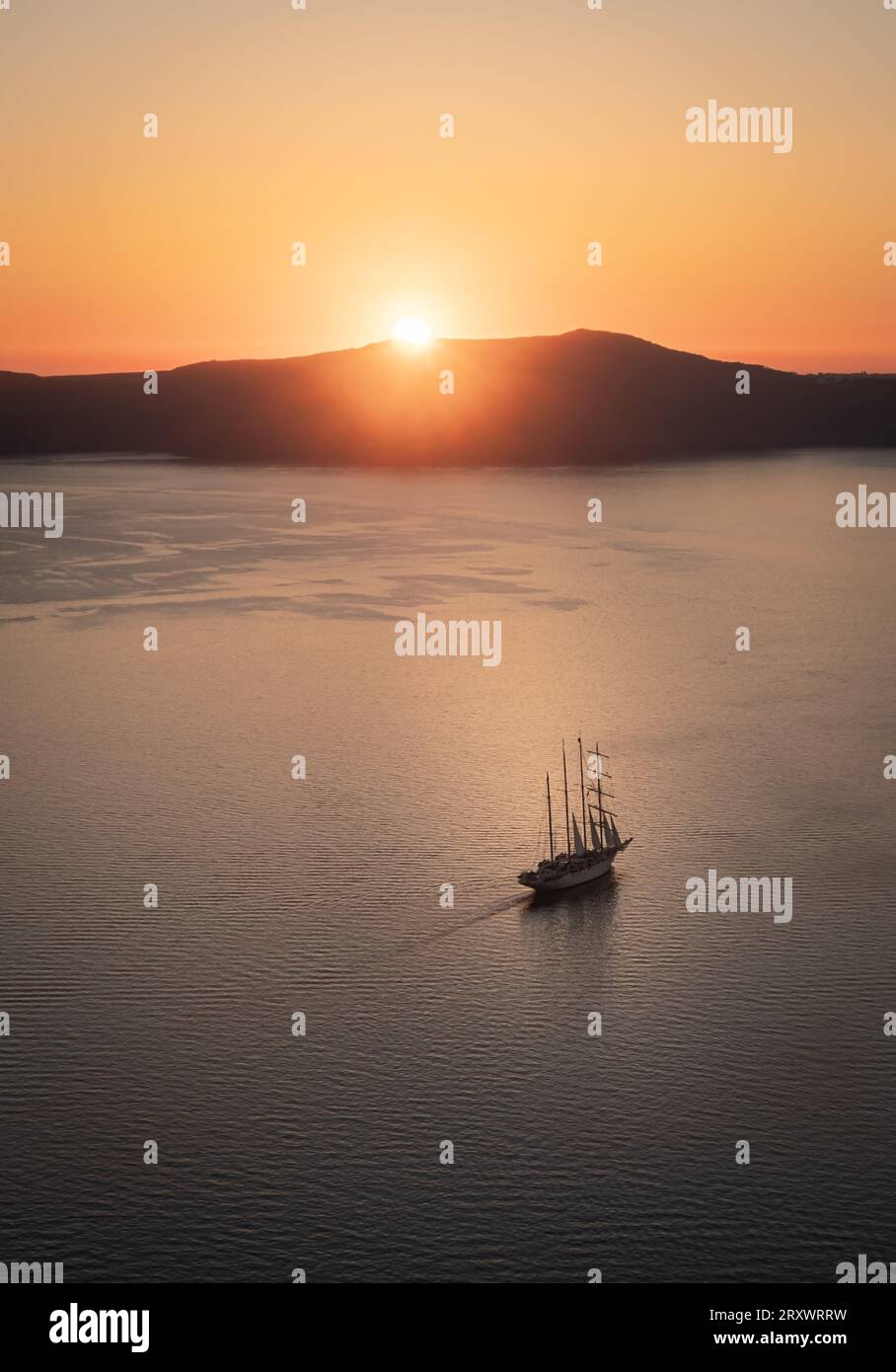 The bay off Thera, Santorini with sun just setting behind the island of ...
