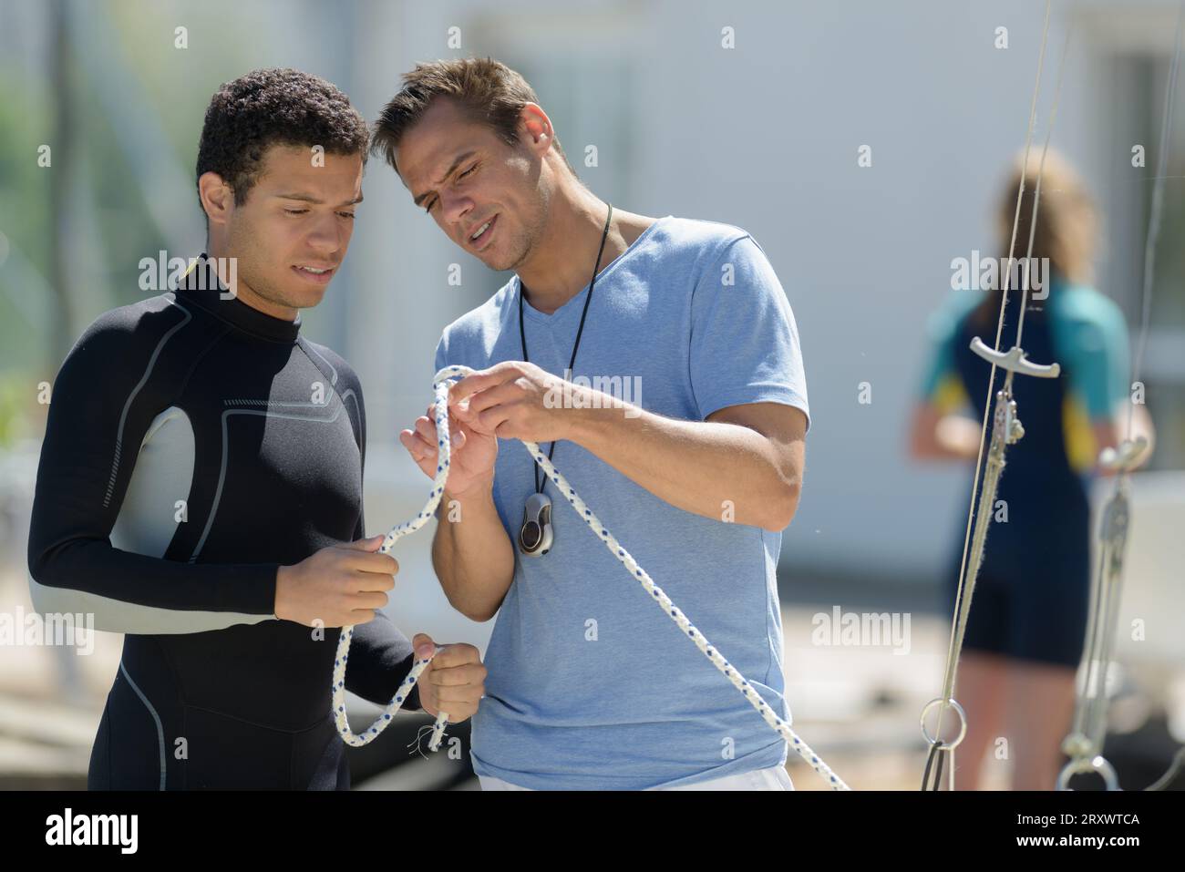 young man in wetsuit learning how to knot rope Stock Photo - Alamy