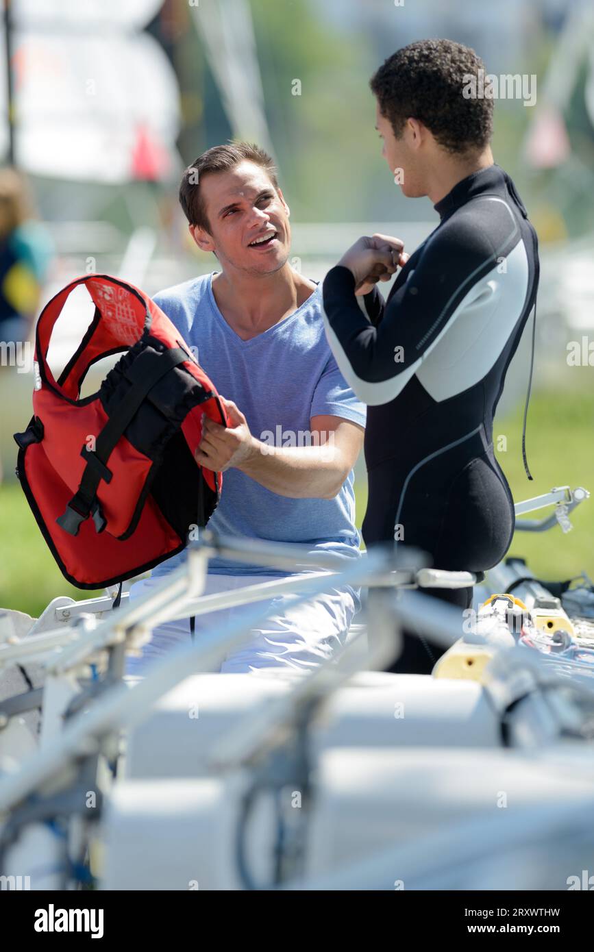 man on wetsuit listening to other man Stock Photo