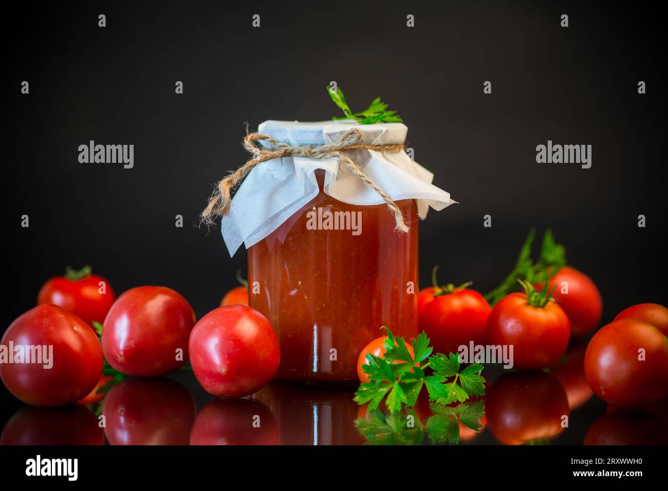 Cooked homemade tomato juice canned in a jar of natural tomatoes, isolated on black background