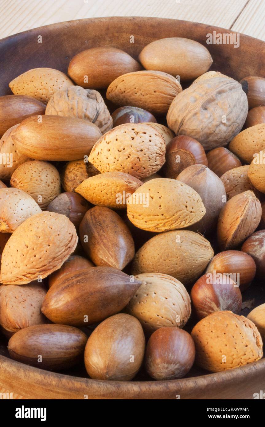 Wooden bowl containing a mixture of whole nuts. - John Gollop Stock Photo