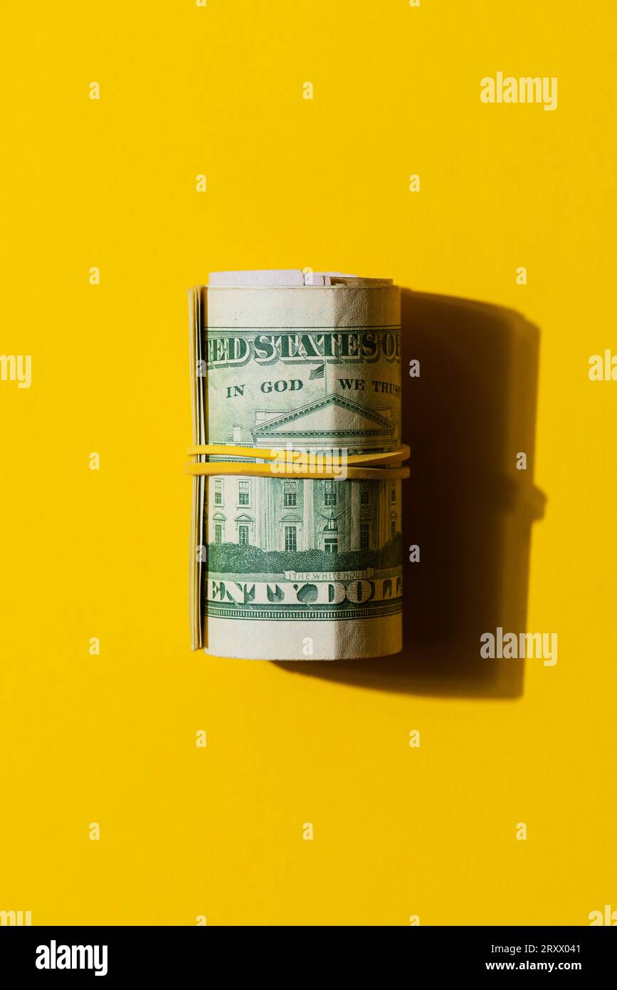 Wad of 100 USD dollar banknote bills on a yellow background, Roll of American dollar banknote bills on a yellow background Stock Photo