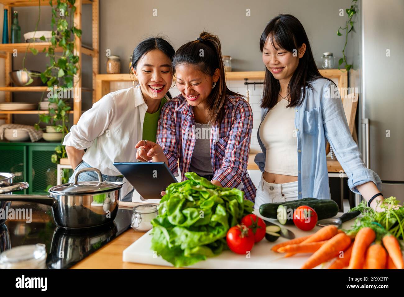 Happy beautiful chinese women friends bonding at home and cooking delicious meal together- Playful pretty asian female adults meeting and having fun a Stock Photo