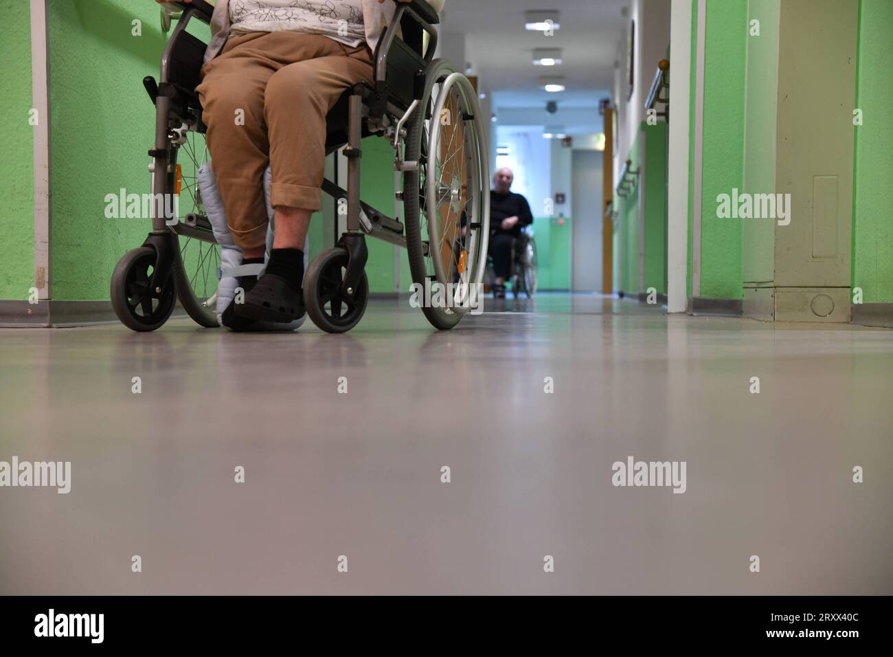 Ein Mann sitzt in einer Pflegeeinrichtung auf einem Flur im Rollstuhl und wartet. Symbolfoto: Pflege, Altenheim, Senioren, Alte, Pflege, Pflegeeinrichtung, Heim, Krankenhaus, Älterwerden *** A man sits in a wheelchair in a hallway in a nursing facility waiting symbol photo care, nursing home, seniors, old, care, nursing facility, home, hospital, aging bub Stock Photo