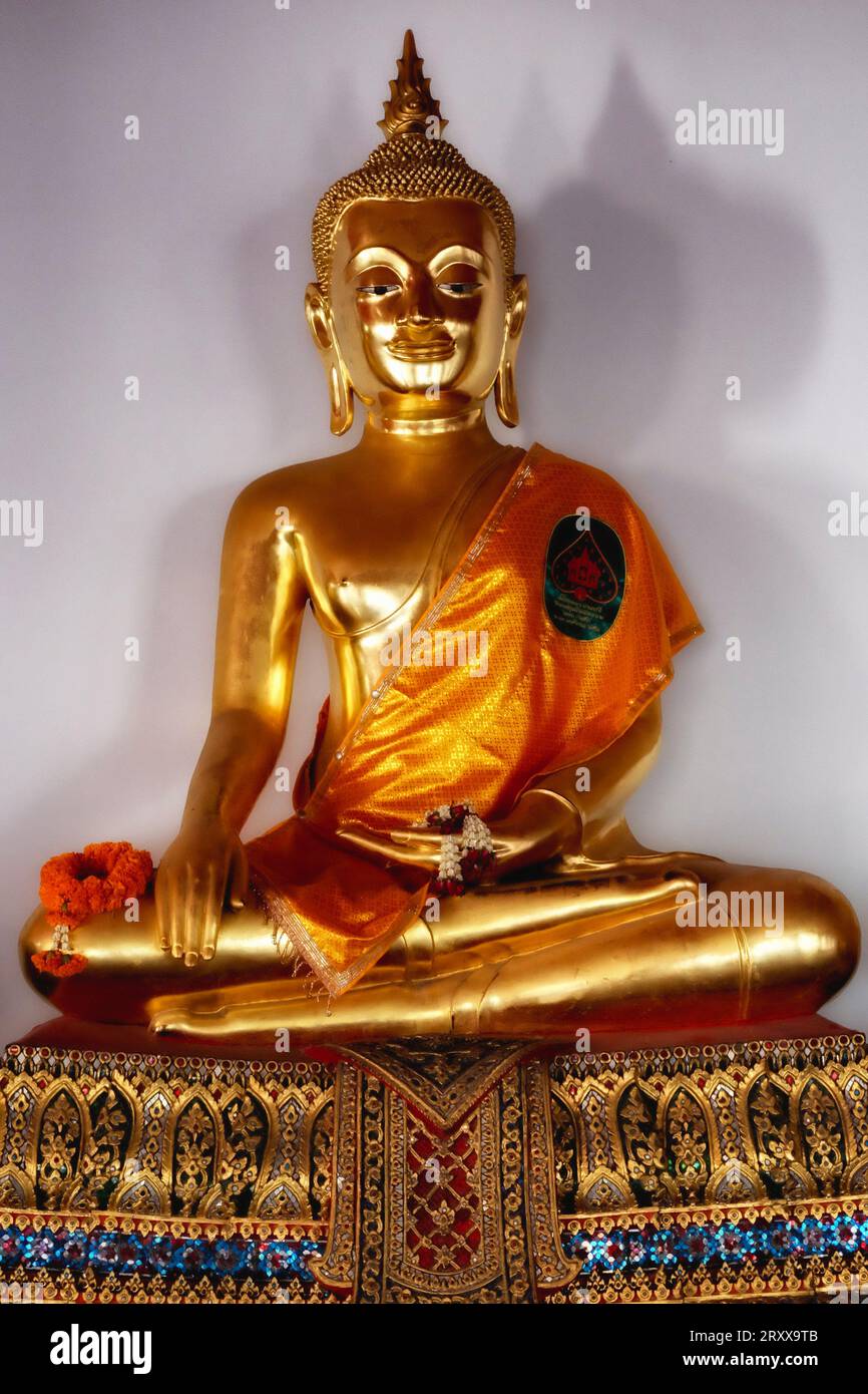A golden Buddha statue seated in the lotus position on a pedestal Stock ...