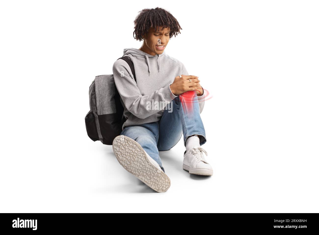 African american male student sitting on the floor and holding his injured knee marked with red isolated on white background Stock Photo