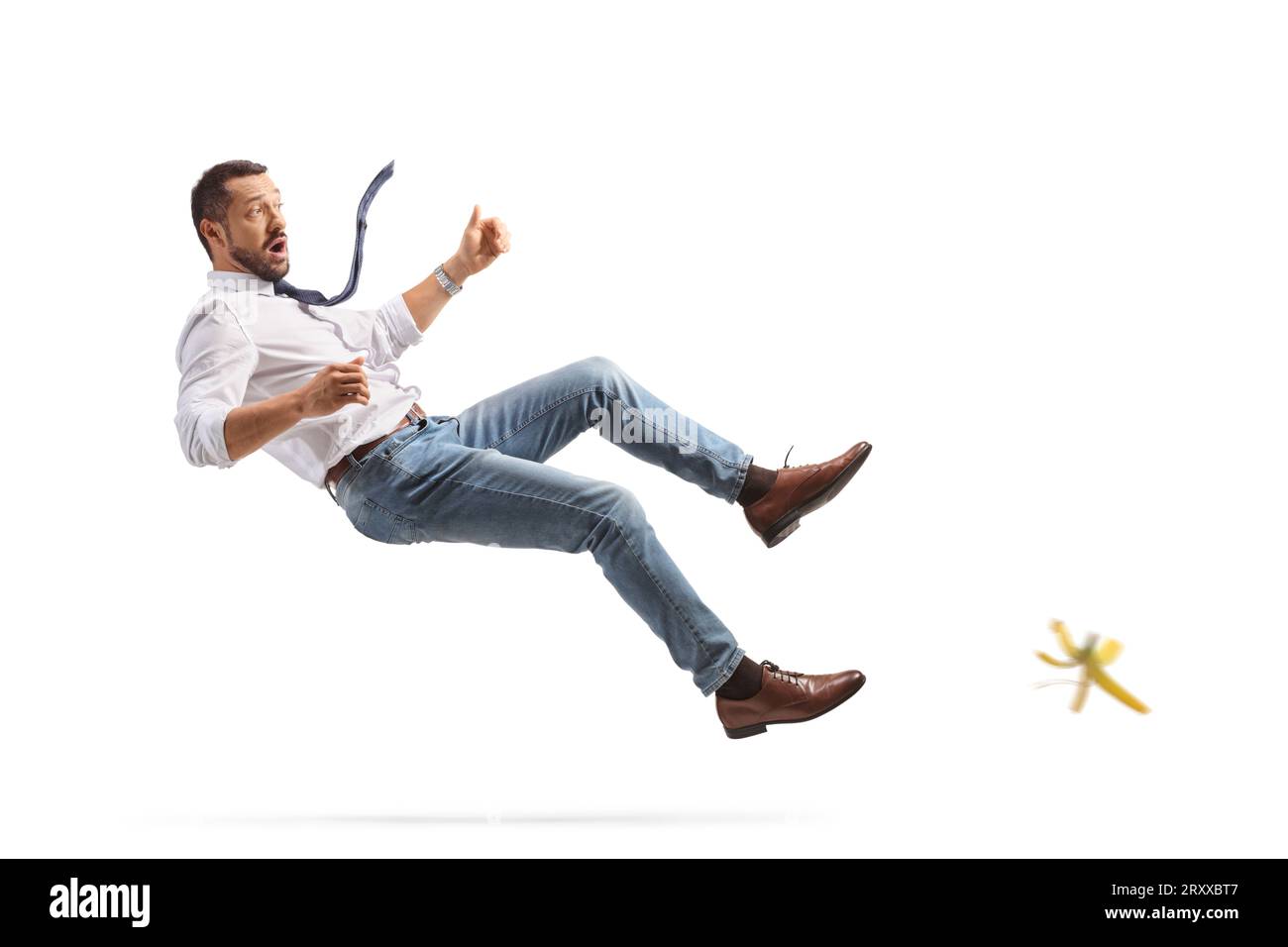 Full length profile shot of a young man falling on a banana skin isolated on white background Stock Photo