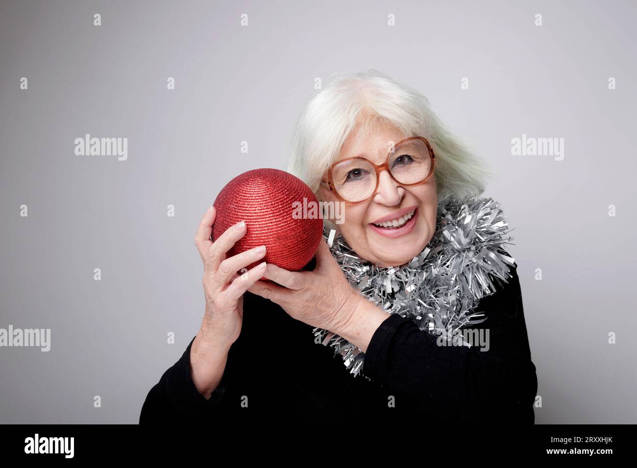 older woman with gray hair and Christmas ornaments Stock Photo