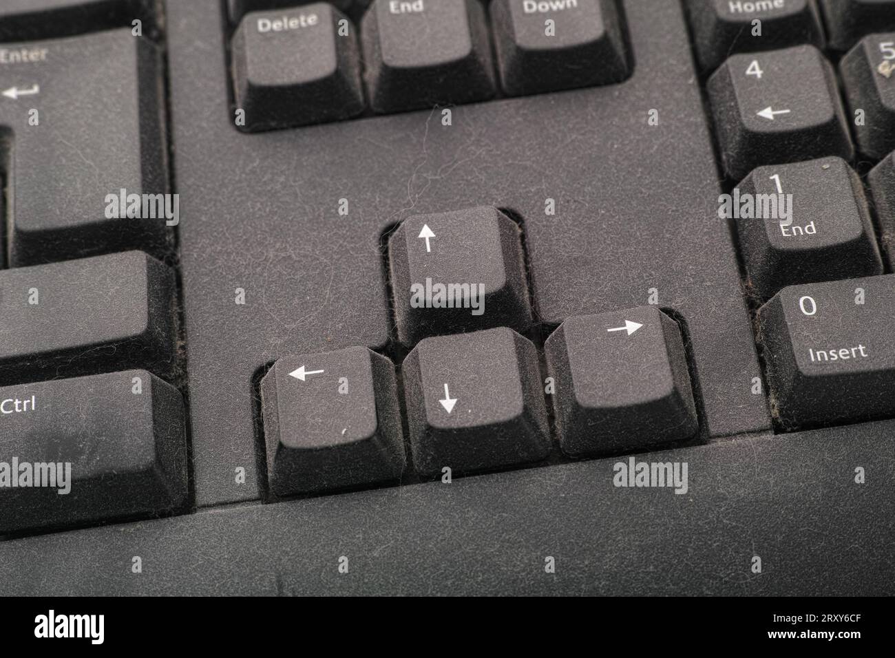 The arrow keys of a black dusty computer keyboard. Close up. Stock Photo