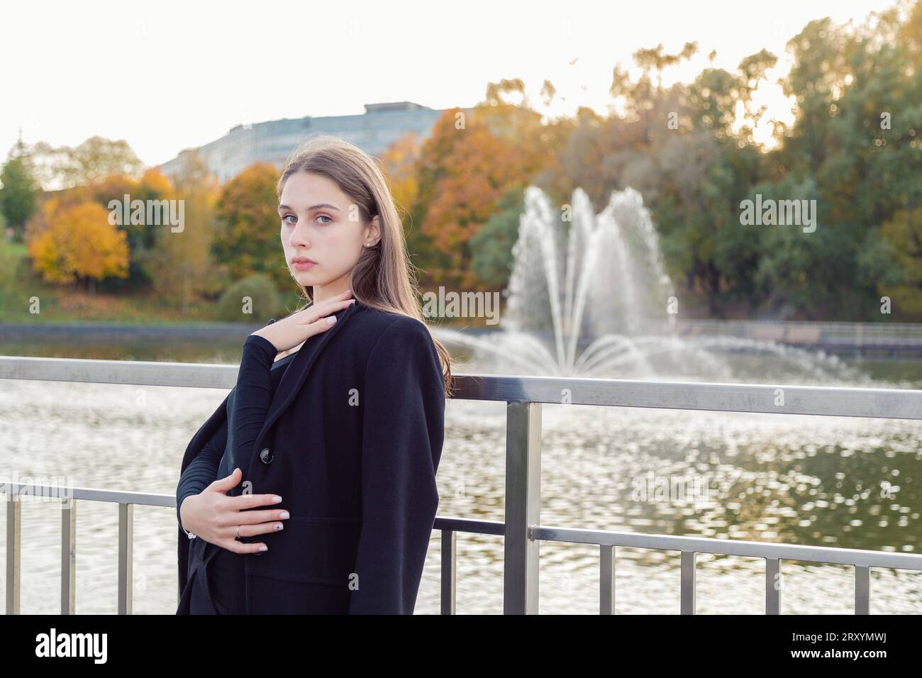 Portrait of a girl on a bridge near a pond in a city park against the ...