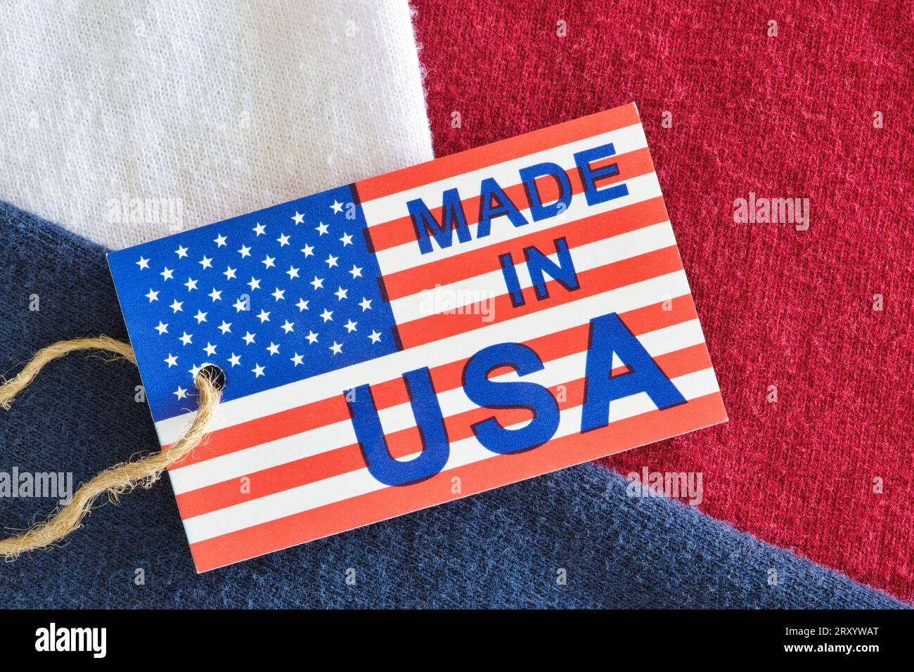 Made in USA label sitting on top of red, white and blue clothing shirts as an economy concept. Flat lay macro image with patriotic background details. Stock Photo