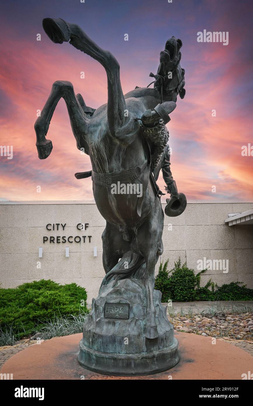 'Early Rodeo' titled bronze rodeo cowboy sculpture by artist Richard Terry, stands before Prescott City Hall, AZ, celebrating 100 years of rodeo with Stock Photo