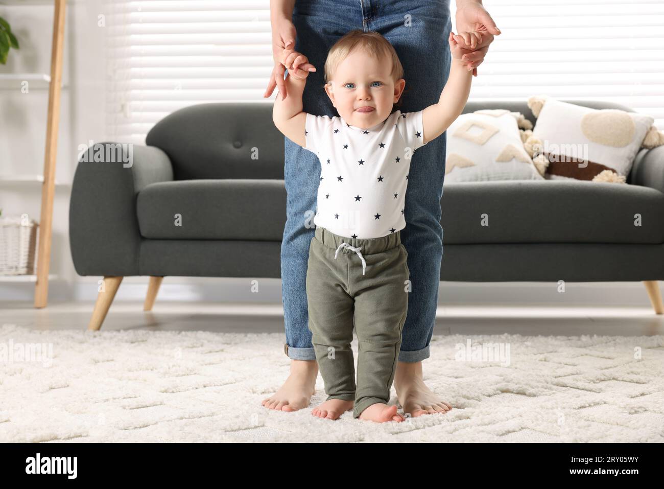 Walk On Rug Mother supporting her baby son while he learning to walk on carpet at ...