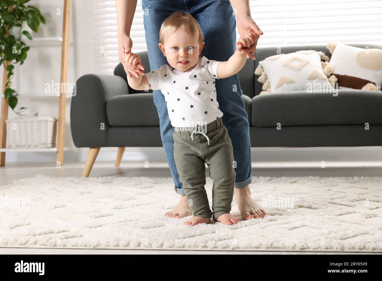 Walk On Rug Mother supporting her baby son while he learning to walk on carpet at ...