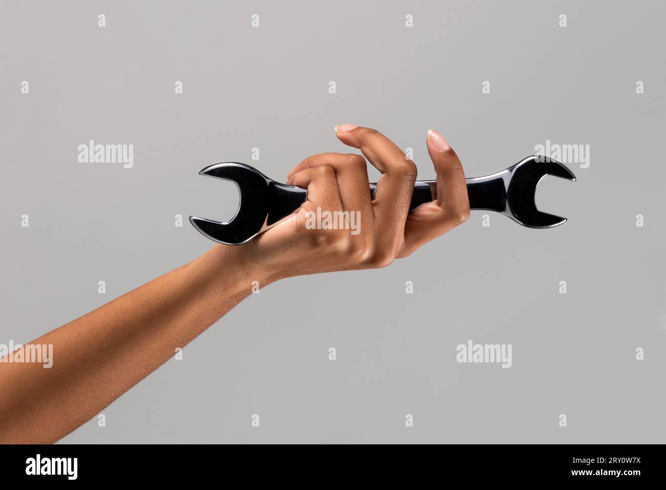 Studio shot of unrecognizable African American female with screw wrench in hand against gray background Stock Photo