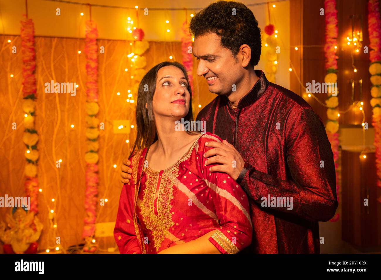 Happy young Indian couple in traditional dress looking at each other ...