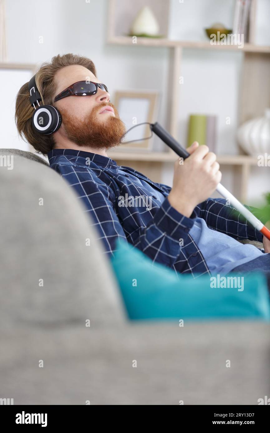 blind man on a sofa using headphones Stock Photo