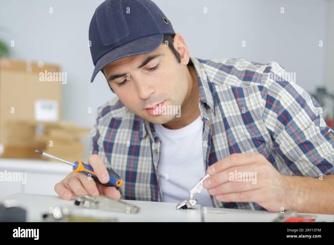 man fitting hinge to kitchen cupboard Stock Photo Alamy
