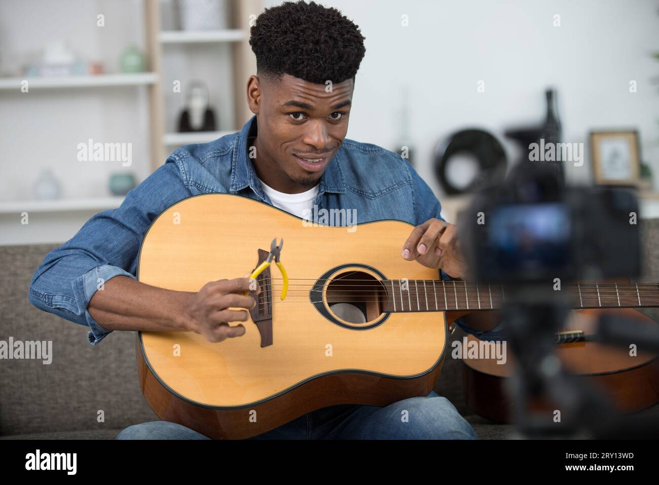 man recording tutorial showing how to repair guitar strings Stock Photo