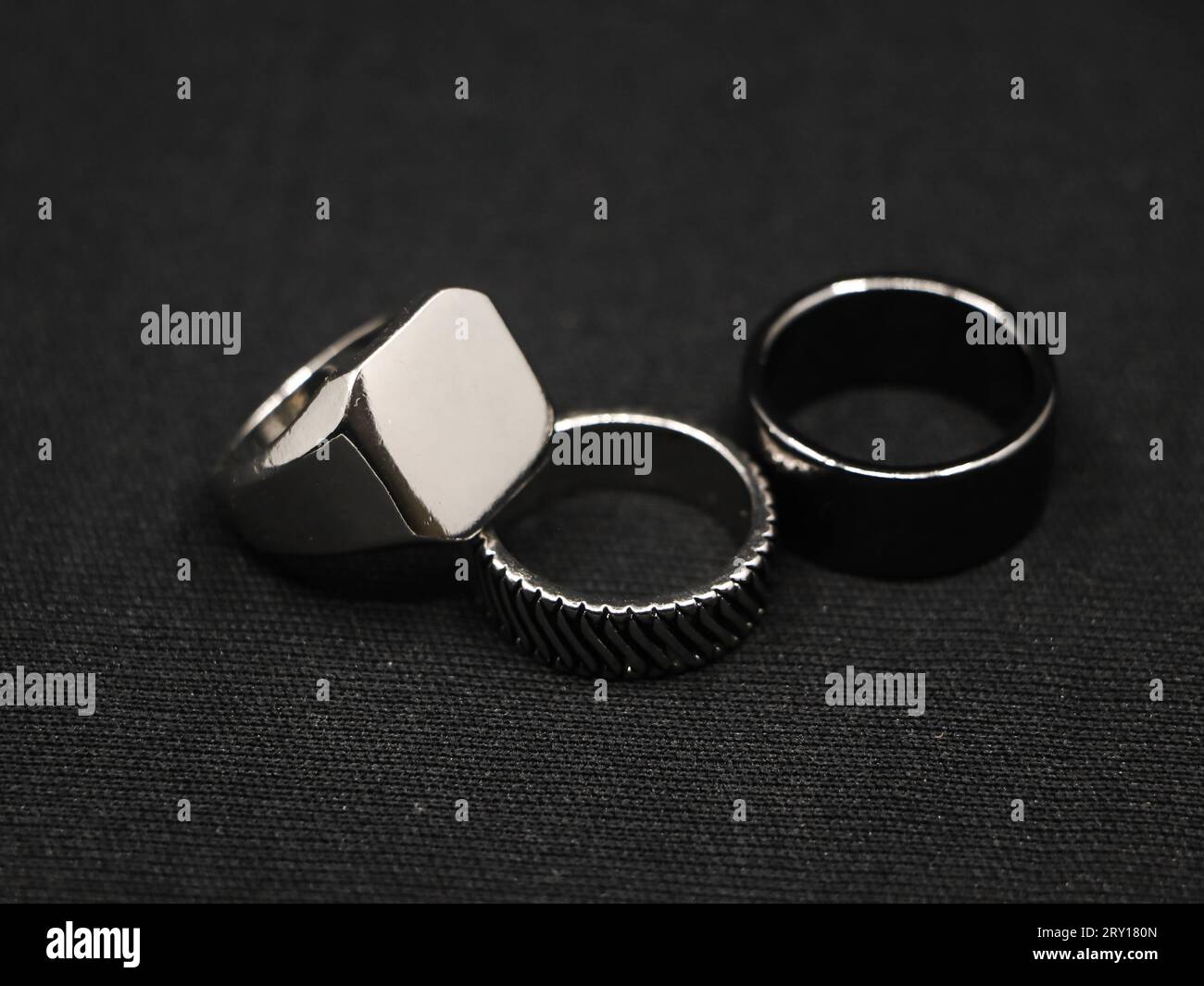 closeup of metallic platinum luxury rings with minimalist design from a fashion jewellery store isolated in a black background Stock Photo