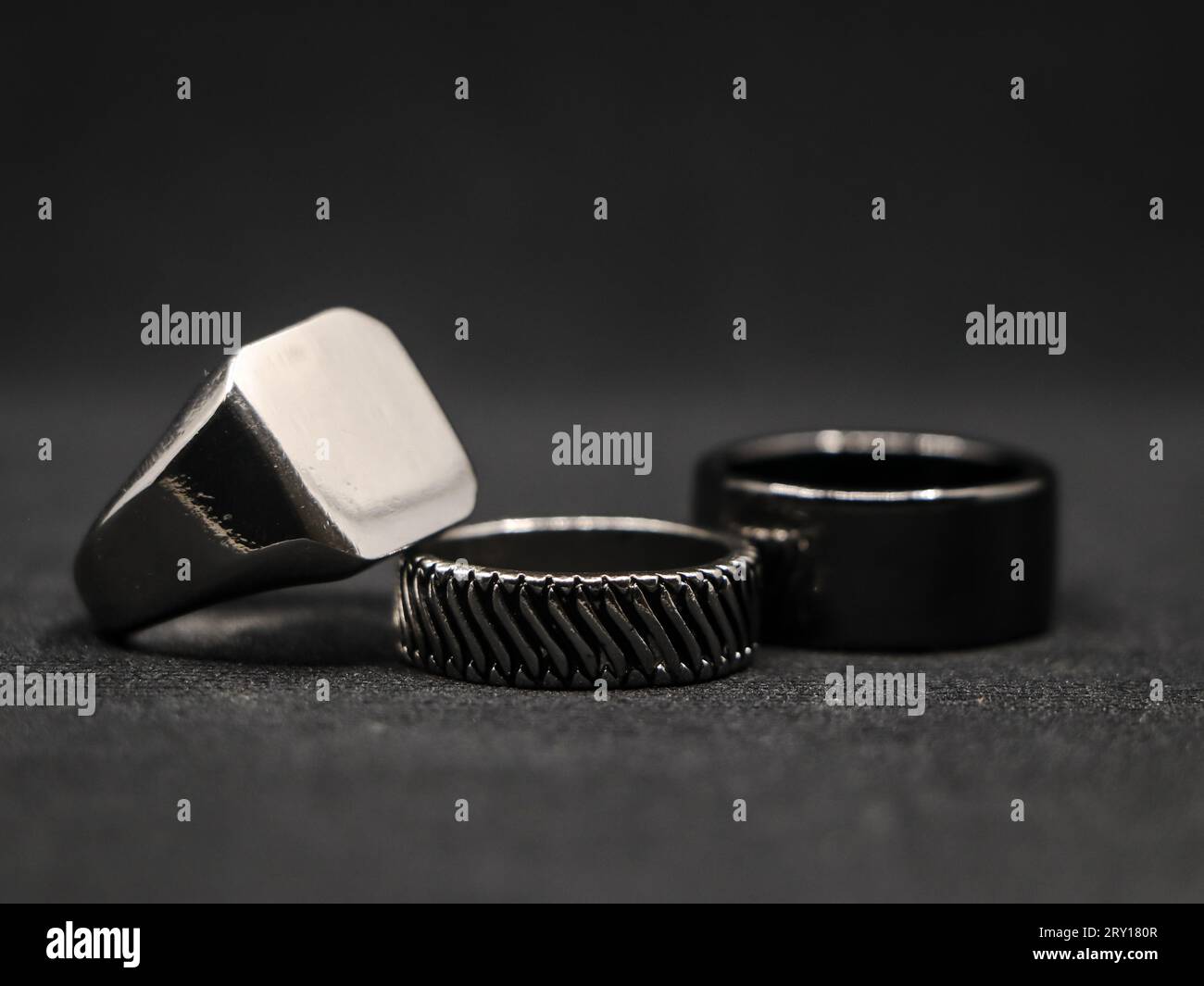 closeup of metallic platinum luxury rings with minimalist design from a fashion jewellery store isolated in a black background Stock Photo