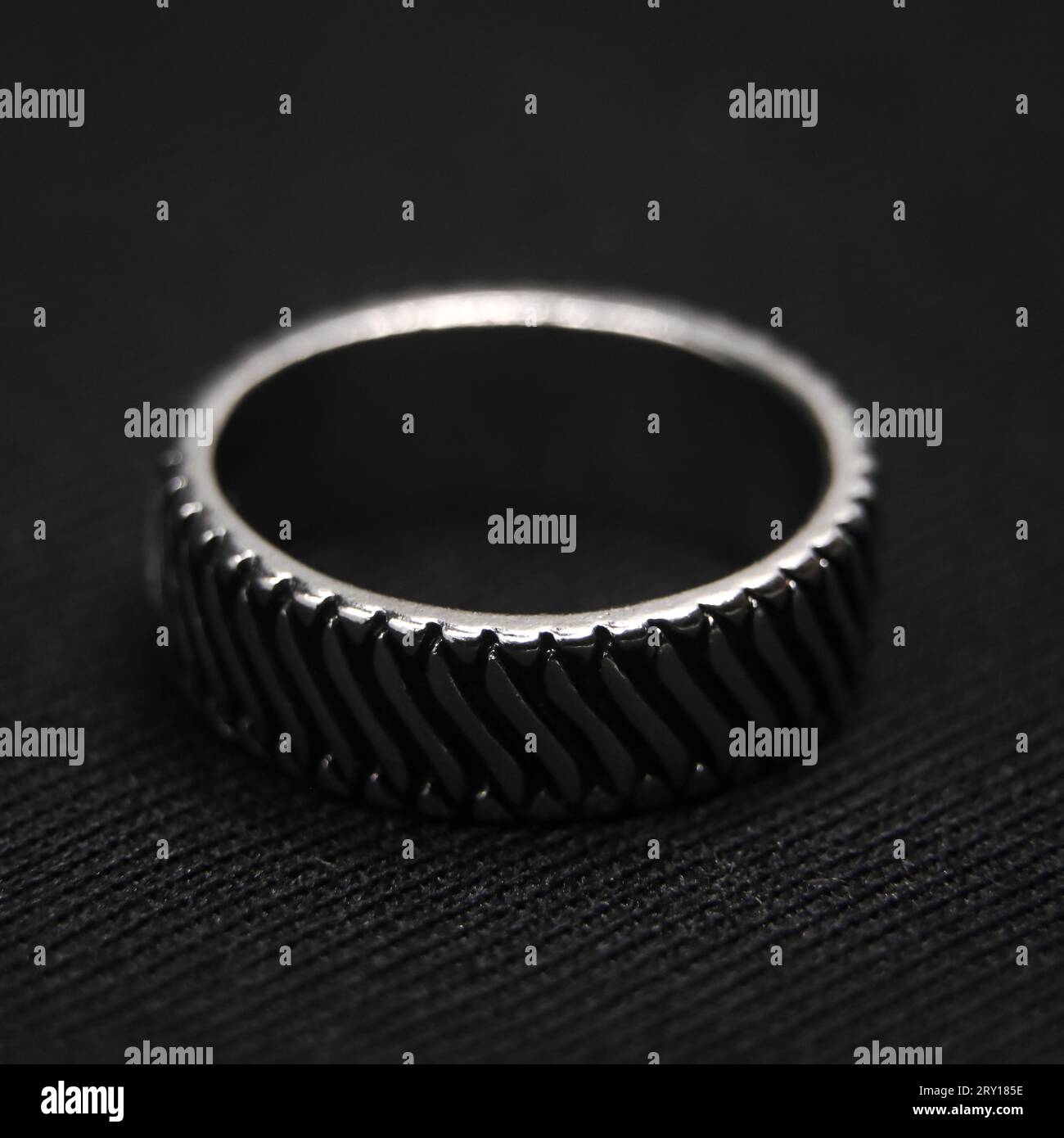 closeup shot of a circular platinum ring with a neatly cut design isolated in a black background Stock Photo