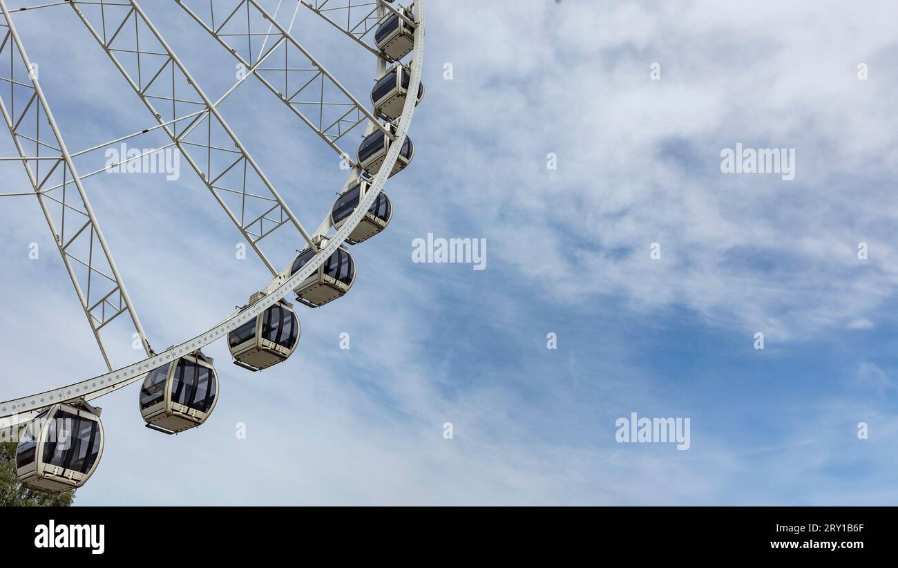 passenger cabins on modern metal Ferris wheel against blue sky in Amusement park. Popular tourist attraction Stock Photo