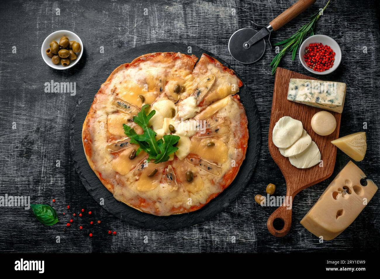 Italian pizza with different sorts of cheese on a stone and a black scratched chalk board