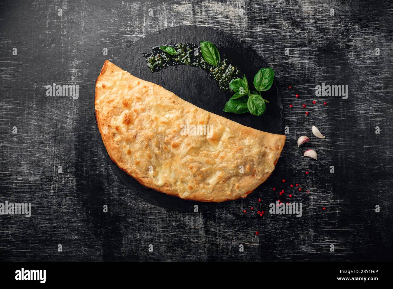 Traditional Italian pizza calzone with ingredients on a stone and dark ...
