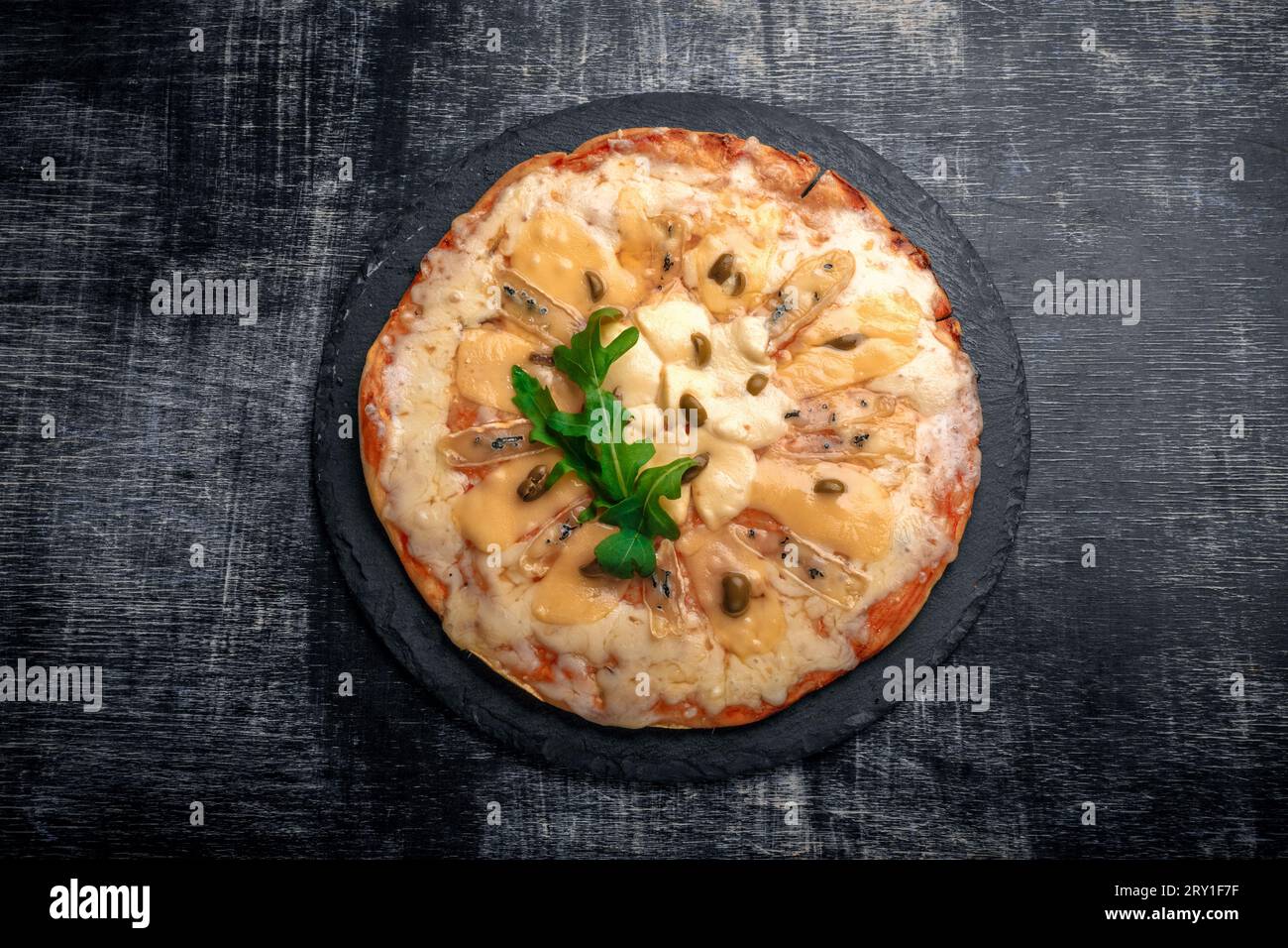 Italian pizza with different sorts of cheese on a stone and a black scratched chalk board