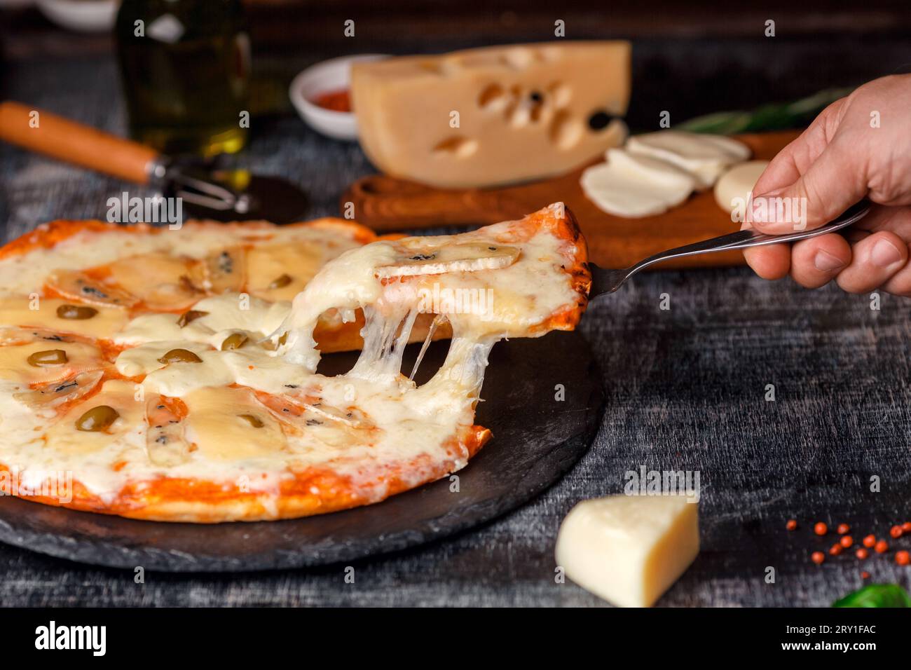 Italian pizza with different sorts of cheese on a stone and a black scratched chalk board