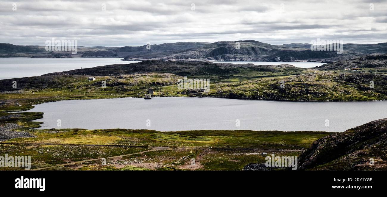 Small cold lake, tundra with rocks and hills. Northern nature of Teriberka, Kola Peninsula, Russia. Loneliness, wild conditions, No people Stock Photo