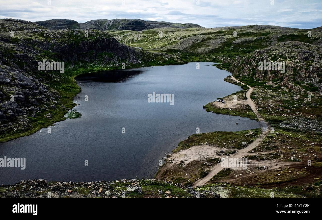 Small cold lake, tundra with rocks and hills. Northern nature of Teriberka, Kola Peninsula, Russia. Loneliness, wild conditions, No people Stock Photo