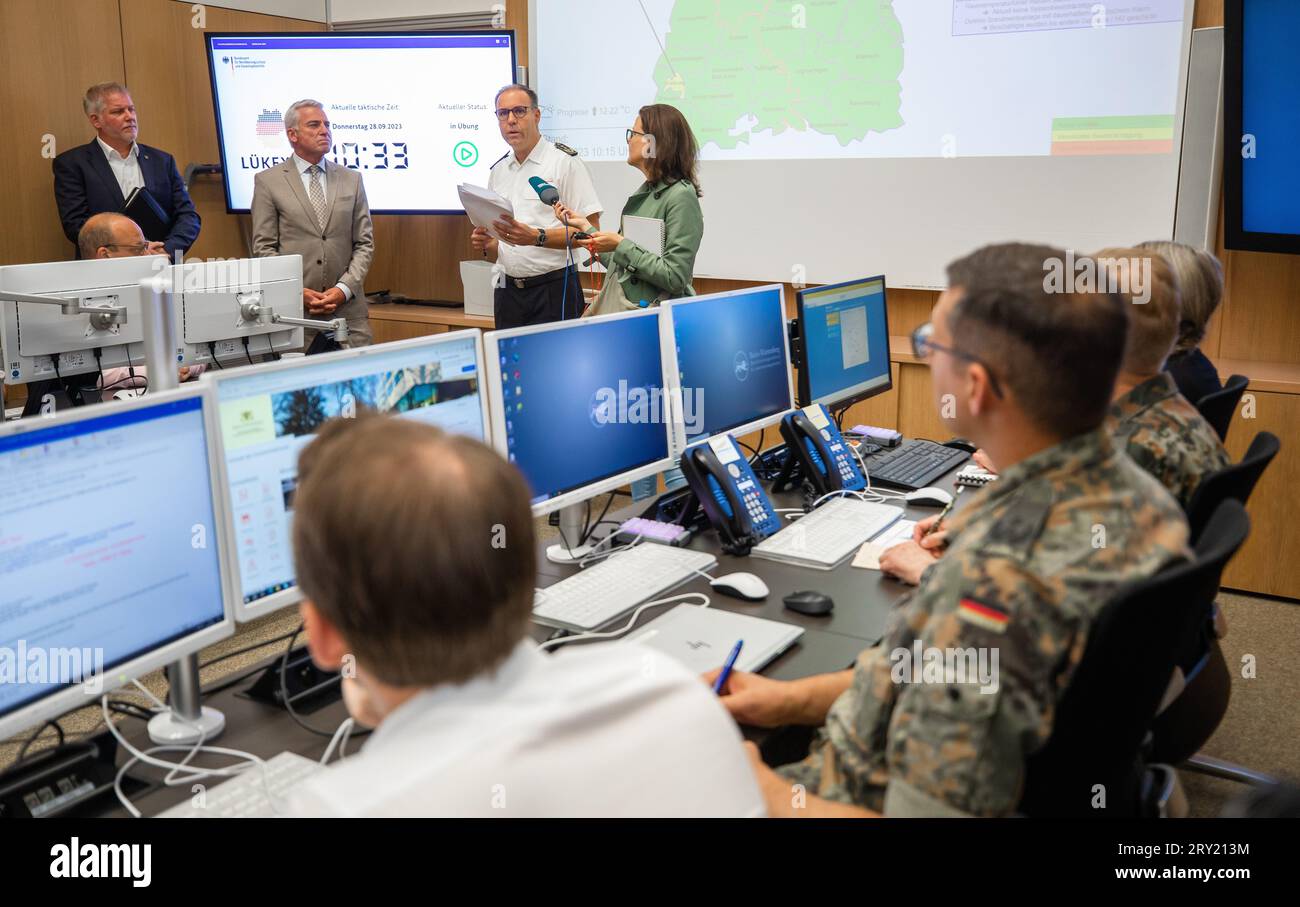 28 September 2023, Baden-Württemberg, Stuttgart: Thomas Egelhaaf (back, 3rd from left), state fire director of Baden-Württemberg, explains the simulation of a major cyberattack in the situation center at the Ministry of the Interior next to Thomas Strobl (2nd from left, CDU), Minister of the Interior of Baden-Württemberg. Under the name 'Lükex 23,' Baden-Württemberg is one of eight German states, along with the German Armed Forces, the German Federal Police and several federal authorities, to train for the event of a major cyberattack on the government and administration. Photo: Christoph Schm Stock Photo