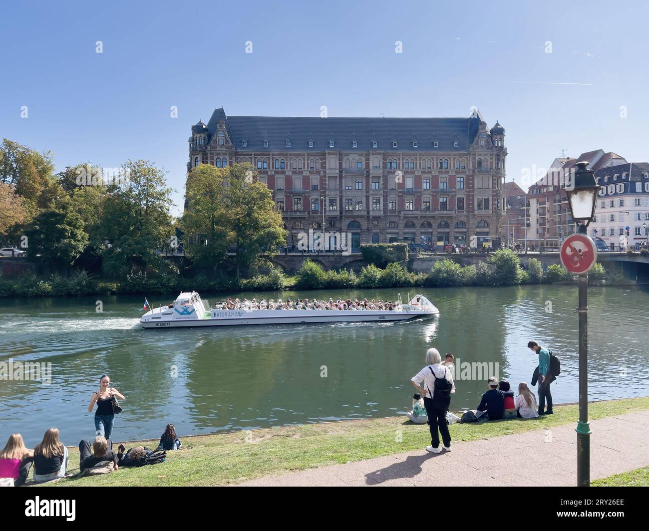 Strasbourg, France - Sep 27, 2023: On a bright summer day, the Ill River in  Strasbourg is bustling with Batorama tourist boats, while the impressive  Residence Universitaire Gallia student dormitory stands majestically