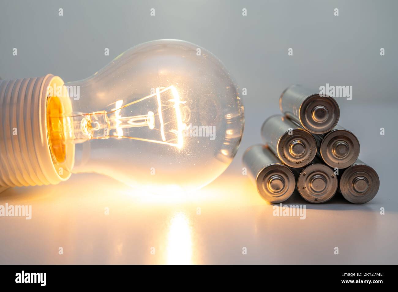 Light bulb turned on, with batteries next to it. Accumulation and reuse