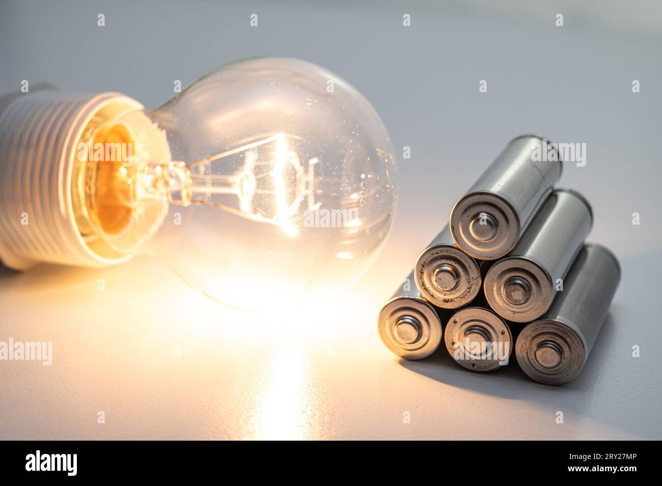 Light bulb turned on, with batteries next to it. Accumulation and reuse
